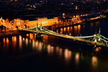 Fototapeta premium the Liberty bridge in Budapest. aerial evening view or blue hour. brightly illuminated steel structure. reflection on water. tourism and travel concept. transportation and design. night photo
