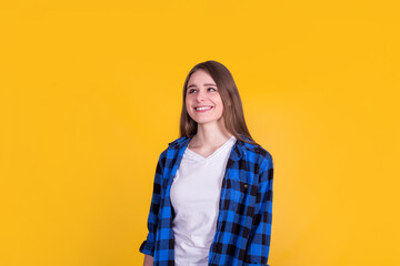 Fototapeta premium Beautiful happy girl in a blue shirt on a yellow background
