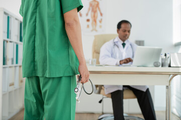 Tired doctor with stethoscope im hands coming to office of chief physician to ask for vacation