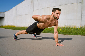 Obraz premium One hand pushup exercise. Athletic doing outdoor workout in the city