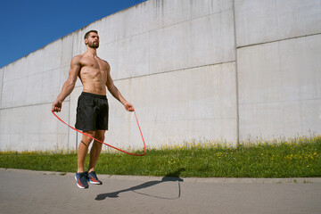 Athletic man training with a jumping rope outdoors