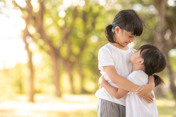 Fototapeta premium Two asian little child girls hugging each other with love in the garden i