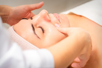 Fototapeta na wymiar Beautician making lymphatic drainage face massage or facelifting massage at the beauty salon