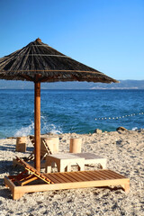Bamboo parasol and wooden deck chair on a beautiful beach in Croatia.