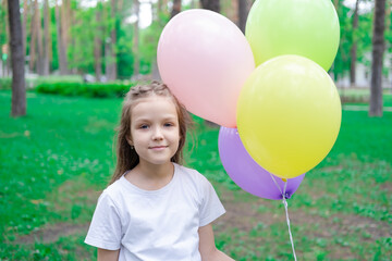 Fototapeta na wymiar pretty preschool girl having fun playing with hot air balloons outdoors. hollidays, party, birthday, celebration. happy children