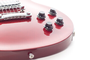 Close up of a red electric guitar with buttons and strings on a white background