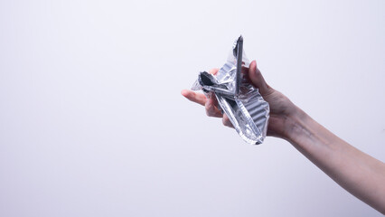 female hand holding foil packaging on gray background