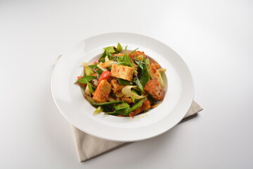 stir fried vegetable with bean curd tofu in spicy sambal chilli sauce in white plate asian halal menu