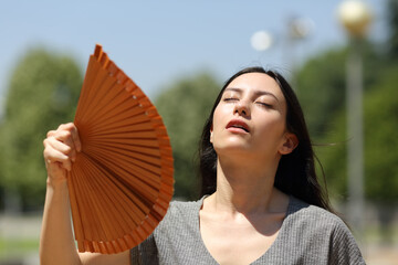 Stressed asian woman fanning suffering heatstroke