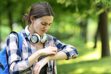 Allergic student scratching arm in a park