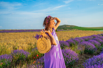 girl in a purple dress with a wreath and ribbons on her head in a lavender field at sunset. Boho...