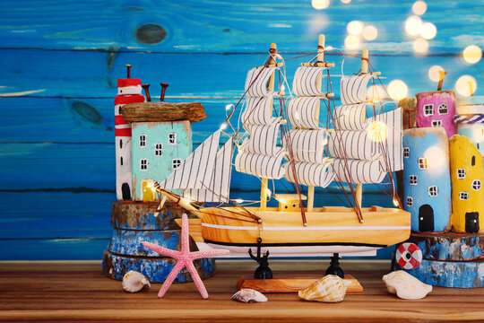 Nautical concept with sea life style objects as boat with lights, driftwood beach houses, seashells and starfish over wooden table