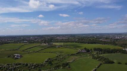 Obraz premium Drone image looking over green farmland with a cloudy sky background. 