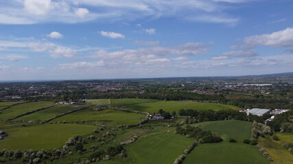 Obraz premium Drone image looking over green farmland with a cloudy sky background. 