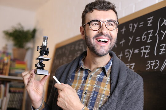 Teacher holding a microscope in classroom 