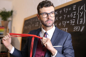 Sexy male teacher with great looks holding red whip - obrazy, fototapety, plakaty
