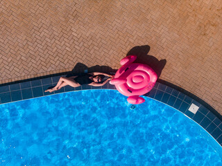 Aerial drone top view of plus size woman in black bikini near swimming poo