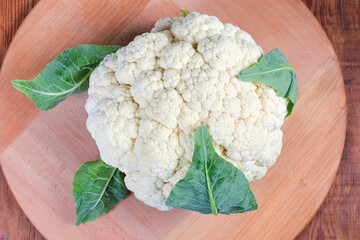 Top view of fresh cauliflower head on wooden serving board