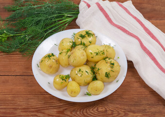 Boiled young potatoes sprinkled with chopped dill on rustic table