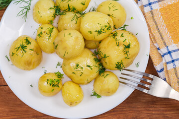 Top view of boiled young potatoes with dill on dish