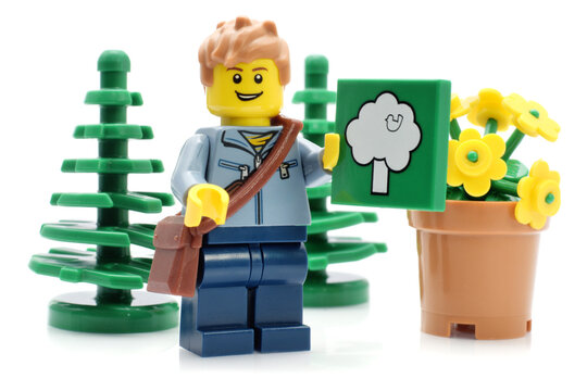 Editorial illustrative image of lego minifigure in ecology concept. Plastic man and green trees isolated on white