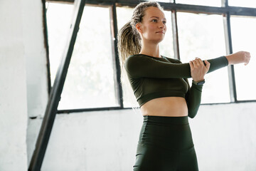 Young sportswoman doing exercise while working out indoors