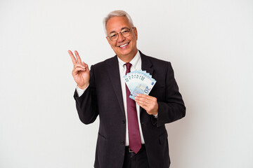Senior american business man holding bills isolated on white background joyful and carefree showing...