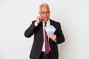 Senior american business man holding bills isolated on white background with fingers on lips keeping a secret.