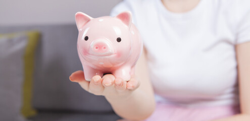 Young woman  putting a coin inside piggy bank as savings for investment