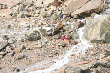 stone in the sand with running water