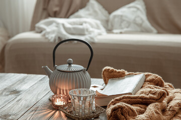 Cozy home composition with tea and a book in the interior of the room.