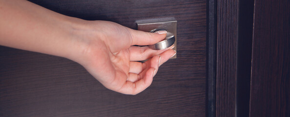 Female hand on metal door handle. Modern interior detail