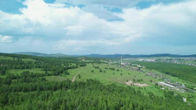 the landscape with nature, blue sky, mountains and a village in the distance is replaced by a rocky cliff. The aerial drone's camera descends down into the Tuim Sinkhole, a tectonic fault