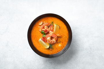 Tom Yum kung Spicy Thai soup with shrimp in a black bowl on a bconcrete background, top view, copy...