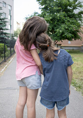 Back view of little girls hugging on a walk.