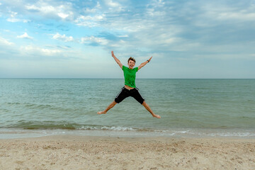 A young guy jumps to the top for joy on the seashore.