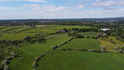 Naklejka premium Aerial view over green farmland with a cloudy sky background. 