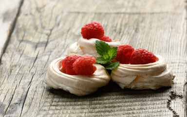baked whipped egg whites cake with raspberries on a gray wooden table, pavlova dessert