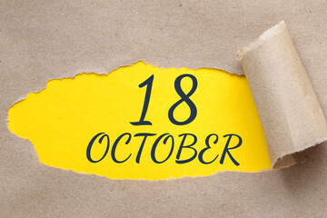 october 18. 18th day of the month, calendar date.Hole in paper with edges torn off. Yellow background is visible through ragged hole.Autumn month, day of the year concept