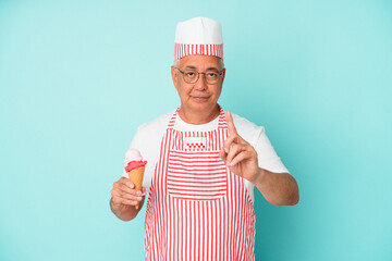 Senior american ice cream maker holding an ice cream isolated on blue background showing number one with finger.