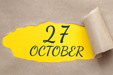 october 27. 27th day of the month, calendar date.Hole in paper with edges torn off. Yellow background is visible through ragged hole.Autumn month, day of the year concept