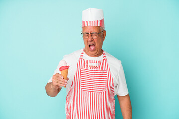 Senior american ice cream maker holding an ice cream isolated on blue background screaming very angry and aggressive.