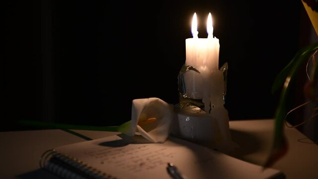 4k The candle is burning, on the table lies a notebook with verses, a pen and a white calla lilly flower. Write at night, inspiration, creativity, poetry, zoom in