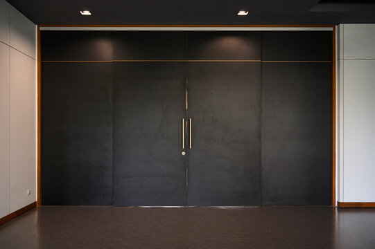 Large black sliding wooden door closed shut. Empty room interior.