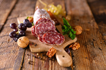 sausage on wooden background with grape and walnut