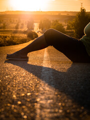 Girl sitting on her back on the road with a sunset. Image of tifestyle, relax and travel