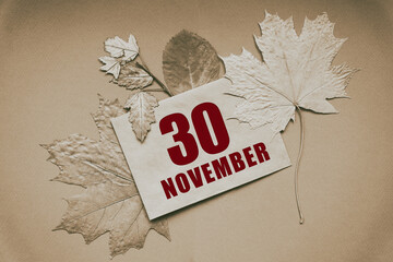 november 30. 30th day of month, calendar date.Envelope with the date and month, surrounded by autumn leaves on brown background.Autumn month, day of year concept