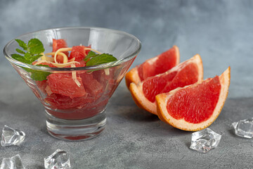 Summer salad with grapefruit on a light background with herbs.