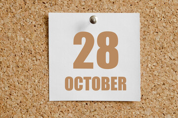 october 28. 28th day of the month, calendar date.White calendar sheet attached to brown cork...