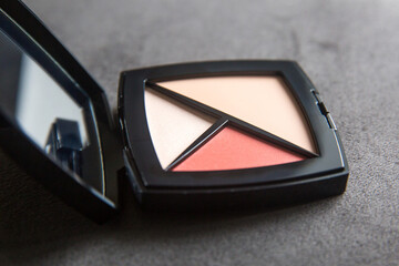 Make up face contouring kit: foundation concealer, highlighter and color blush. Decorative cosmetics in black box on grey background. Make up and beauty concept.